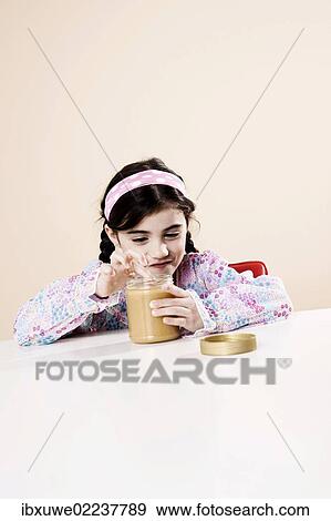 Stock Photo - Girls nibbling enjoyably from a glass of honey. Fotosearch