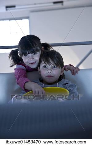 Stock Image - Girls with popcorn watching television. Fotosearch