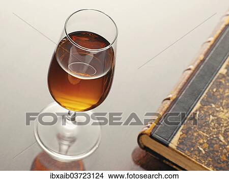 Glass of sherry beside an old book View Large Photo Image Picture - Glass of sherry beside an old book. Fotosearch