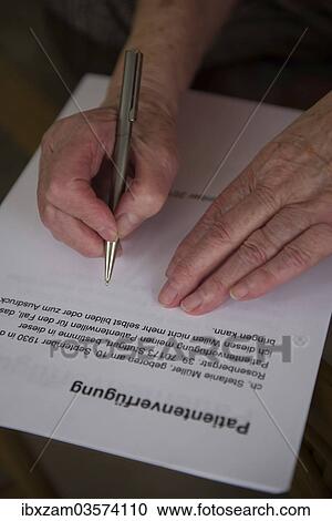 Stock Image - "Hands of a 82-year-old woman signing a living will, Germany, Europe". Fotosearch