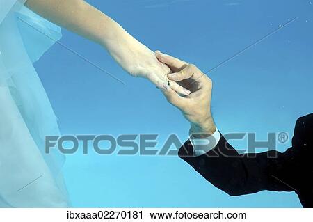 Stock Image - "Hands of bride and groom, ring, underwater wedding in pool, Odessa, Ukraine, Eastern Europe, Europe". Fotosearch
