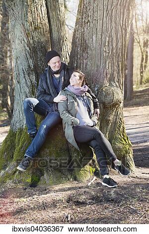 "Happy young couple sitting by a tree, Sweden, Europe" View Large Photo Image Stock Photo - "Happy young couple sitting by a tree, Sweden, Europe". Fotosearch