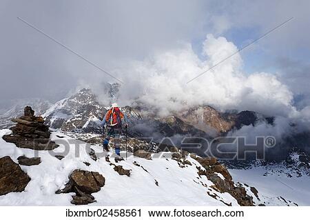 Stock Image - "Hiker on Lorcherspitz Mountain, looking towards Weissenbrunnspitz Mountain and Zufrittspitz Mountain in heavy fog, Alto Adige, Italy, Europe". Fotosearch