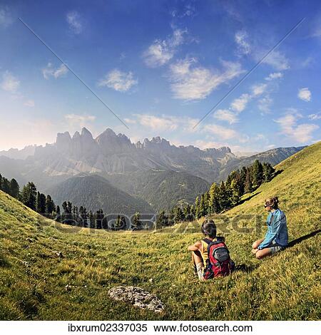 "Hikers relaxing in a meadow enjoying the view of the Geisler group, Aferer Geisler mountains, Villnoesstal valley, province of Bolzano-Bozen, Italy, Europe" View Large Photo Image Stock Photography - "Hikers relaxing in a meadow enjoying the view of the Geisler group, Aferer Geisler mountains, Villnoesstal valley, province of Bolzano-Bozen, Italy, Europe". Fotosearch