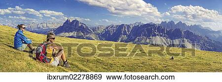 Stock Photo - "Hikers sitting on the Aferer Alm alp on Plosen mountain, enjoying the view of the Afer Geisler group and Peitlerkofel mountain, Wuerzjoch ridge, Villnoesstal valley, Dolomites, province of Bolzano-Bozen, Italy, Europe". Fotosearch