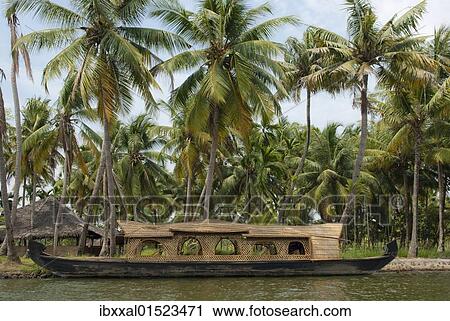 Stock Image - "Houseboat in front of palm trees, Kerala backwaters, Kochi, Kerala, India, Asia". Fotosearch