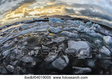 Stock Photography - "Icebergs, dramatic clouds, Jokulsarlon glacial lagoon in the evening sun, Vatnajokull Glacier, East, Iceland, Europe". Fotosearch