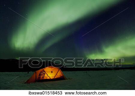 Stock Image - "Illuminated expedition tent and traditional wooden snow shoes, Northern Lights, Polar Lights, Aurora Borealis, green, purple, blue, near Whitehorse, Yukon Territory, Canada, North America". Fotosearch