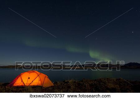 Stock Photo - "Illuminated expedition tent, Northern lights, Polar Aurorae, Aurora Borealis, green, reflections in water, Lake Laberge, near Whitehorse, Yukon Territory, Canada, North America". Fotosearch