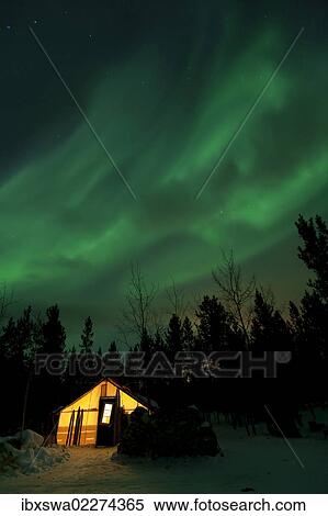Stock Photography - "Illuminated, lit wall tent, cabin with swirling northern polar lights, Aurora Borealis, green, near Whitehorse, Yukon Territory, Canada, North America". Fotosearch