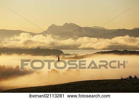 "Lake Chiemsee and the church steeple of Greimharting as seen from Ratzinger Hoehe in the early morning, Chiemgau, Upper Bavaria, Bavaria, Germany, Europe" View Large Photo Image Stock Image - "Lake Chiemsee and the church steeple of Greimharting as seen from Ratzinger Hoehe in the early morning, Chiemgau, Upper Bavaria, Bavaria, Germany, Europe". Fotosearch