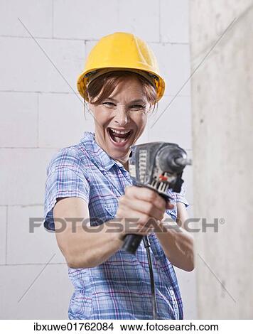 Laughing craftswoman with hard hat and power drill View Large Photo Image Picture - Laughing craftswoman with hard hat and power drill. Fotosearch