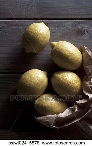 Stock Photo - Lemons with a paper bag on a wooden background. Fotosearch