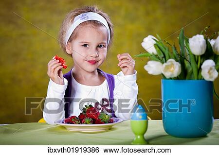 Little blonde girl eating strawberries at a table View Large Photo Image Stock Photograph - Little blonde girl eating strawberries at a table. Fotosearch
