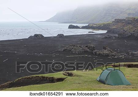 Stock Image - "Lonely tent on a meadow in the early morning fog, Osthoefn, Heradsfloi bay, Greenland Sea, Atlantic coast, Iceland, Europe". Fotosearch
