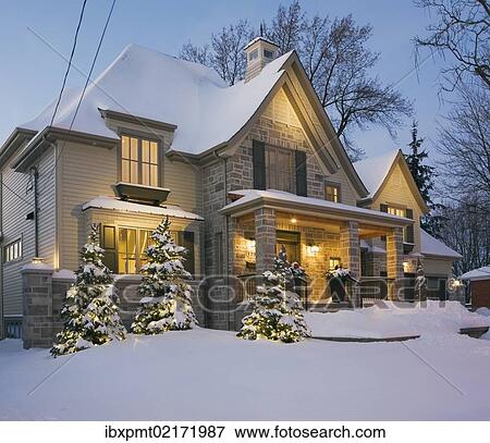 Stock Photo - "Luxurious residential cottage style home with illuminated evergreen trees at dusk in winter, Quebec, Canada, North America". Fotosearch