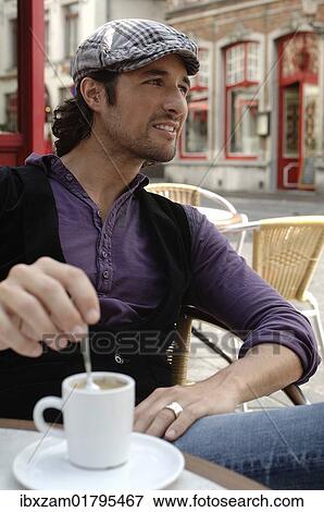 "Man, early 30s, wearing casual clothes sitting in an outdoor cafe stirring a coffee cup, smiling" View Large Photo Image Stock Photo - "Man, early 30s, wearing casual clothes sitting in an outdoor cafe stirring a coffee cup, smiling". Fotosearch