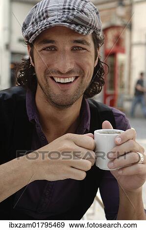 "Man, early 30s, wearing casual clothes sitting in an outdoor cafe holding a coffee cup, smiling" View Large Photo Image Stock Photo - "Man, early 30s, wearing casual clothes sitting in an outdoor cafe holding a coffee cup, smiling". Fotosearch