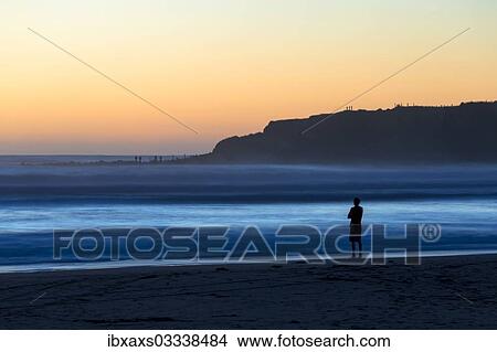 Picture - "Man on the beach with surf, Opunake, Taranaki Region, New Zealand, Oceania". Fotosearch