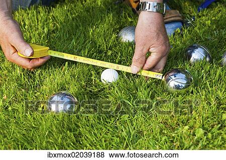 Stock Photo - "Man playing boules, petanque, measuring the distances between the balls, Hesse, Germany, Europe". Fotosearch