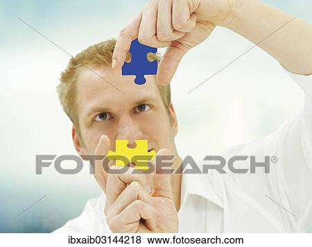 Man putting pieces of a jigsaw puzzle together View Large Photo Image Stock Photo - Man putting pieces of a jigsaw puzzle together. Fotosearch