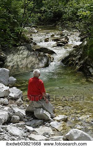 Stock Photo - "Man sitting in the Schwarzach Gorge, Weissbach on the Alpine Road, Schneizlreuth, Upper Bavaria, Bavaria, Germany, Europe". Fotosearch