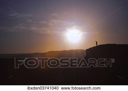 "Man standing on the edge of a cliff at sunset, Valle de la Luna, San Pedro de Atacama, Chile, South America" View Large Photo Image Stock Image - "Man standing on the edge of a cliff at sunset, Valle de la Luna, San Pedro de Atacama, Chile, South America". Fotosearch