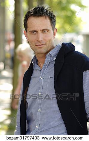Man wearing casual clothes standing in an avenue View Large Photo Image Stock Image - Man wearing casual clothes standing in an avenue. Fotosearch
