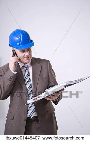 Man with a hard hat on the phone View Large Photo Image Stock Photo - Man with a hard hat on the phone. Fotosearch