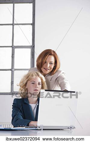 Manager working in an office with a trainee at the computer View Large Photo Image Picture - Manager working in an office with a trainee at the computer. Fotosearch