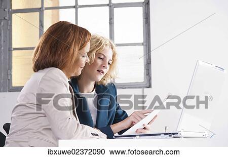 Manager working in an office with a trainee at the computer View Large Photo Image Stock Image - Manager working in an office with a trainee at the computer. Fotosearch