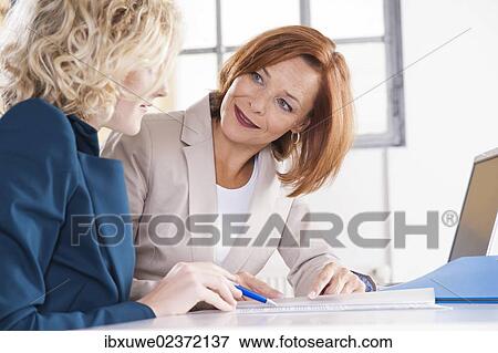 Manager working in an office with a trainee at the computer View Large Photo Image Stock Photo - Manager working in an office with a trainee at the computer. Fotosearch