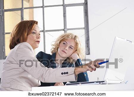 Manager working in an office with a trainee at the computer View Large Photo Image Stock Photo - Manager working in an office with a trainee at the computer. Fotosearch
