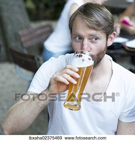 Mann drinking wheat beer in a beer garden View Large Photo Image Stock Photo - Mann drinking wheat beer in a beer garden. Fotosearch