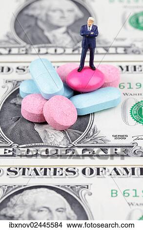 Miniature figurine of businessman standing on medical pills on US dollar bill View Large Photo Image Picture - Miniature figurine of businessman standing on medical pills on US dollar bill. Fotosearch