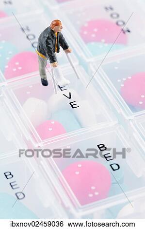 Stock Photograph - Miniature figurine with broken leg on pill box. Fotosearch