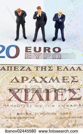 Stock Image - Miniature figurines of businessmen on euro and Greek drachma banknotes. Fotosearch