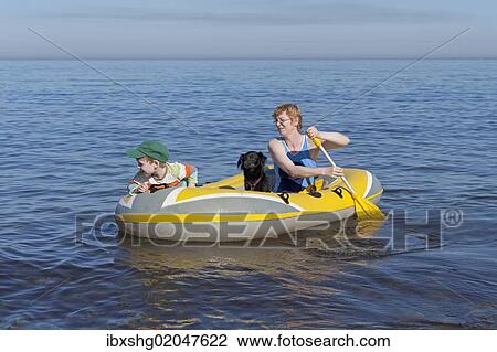Stock Image - "Mother and son with dog in a rubber boat, Kuehlungsborn-West, Mecklenburg-Western Pomerania, Germany, Europe". Fotosearch