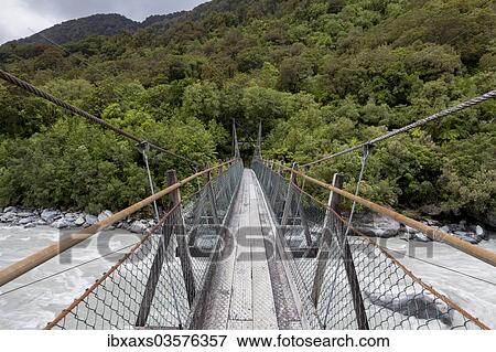 Stock Photo - "Narrow suspension bridge over the Fox River, Fox River, West Coast Region, New Zealand, Oceania". Fotosearch