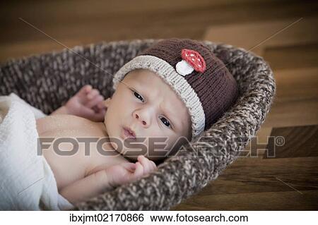 "Newborn baby, 3 weeks, wearing a hat, lying in a basket" View Large Photo Image Stock Photograph - "Newborn baby, 3 weeks, wearing a hat, lying in a basket". Fotosearch