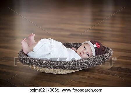 "Newborn baby, 3 weeks, wearing a hat, lying in a basket" View Large Photo Image Stock Photography - "Newborn baby, 3 weeks, wearing a hat, lying in a basket". Fotosearch