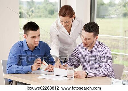 Office team having a meeting around a desk View Large Photo Image Stock Image - Office team having a meeting around a desk. Fotosearch