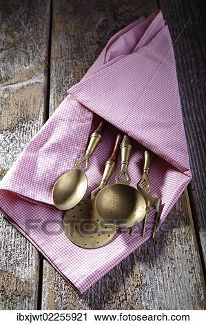 "Old kitchen utensils made of brass wrapped in a kitchen towel, lying on a rustic wooden background" View Large Photo Image Stock Image - "Old kitchen utensils made of brass wrapped in a kitchen towel, lying on a rustic wooden background". Fotosearch