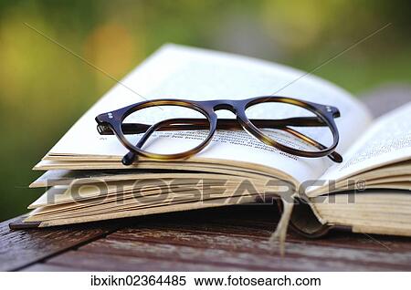 Stock Photography - Old reading glasses with a book in the garden. Fotosearch