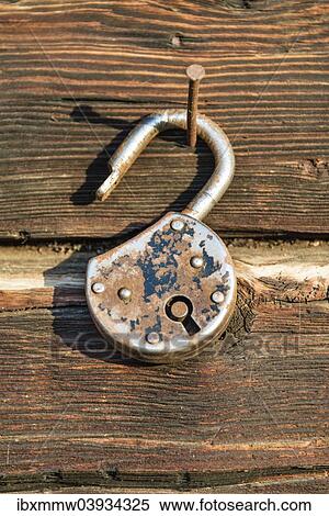 Old rusted lock hanging on a nail on a wooden wall View Large Photo Image Stock Photography - Old rusted lock hanging on a nail on a wooden wall. Fotosearch