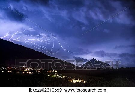 Stock Photo - "Ominous clouds and lightning bolts from thunderclouds over the Stubai Valley near Innsbruck, in the back Mt. Serles and Aldrans and Lans villages, night scene, Innsbruck, Tyrol, Austria, Europe". Fotosearch