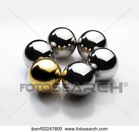 Stock Image - One golden and five silver-coloured metall balls in a circle. Fotosearch