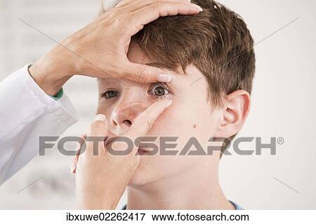 Ophthalmologist explaining the use of contact lenses to a teenage boy View Large Photo Image Stock Photo - Ophthalmologist explaining the use of contact lenses to a teenage boy. Fotosearch