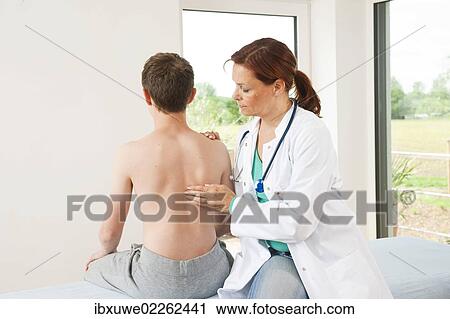 Orthopedic surgeon examining a teenage boy's back View Large Photo Image Stock Image - Orthopedic surgeon examining a teenage boy's back. Fotosearch