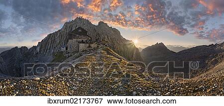Stock Photo - "Panoramic view as seen from Toerlgatterl, Toerlspitze mountain and Meilerhuette mountain lodge at sunrise, with bizarre red clouds in the sky, Garmisch-Partenkirchen, Wetterstein mountain range, Bavaria, Germany, Europe". Fotosearch